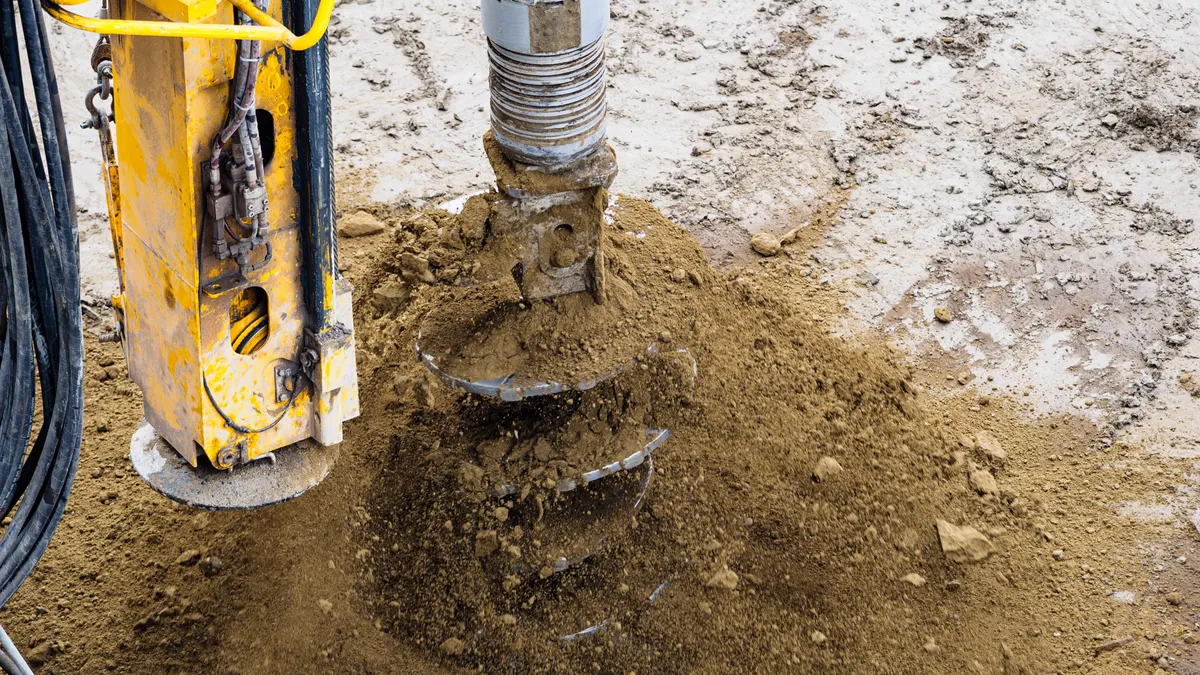 Excavator auger drilling soil for foundation work