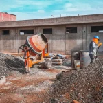 Construction site with gravel, mixer, and worker