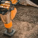 Tamping rammer compacting soil on a construction site